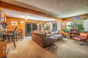 Living area featuring wood walls, a textured ceiling, carpet floors, french doors, and a chandelier