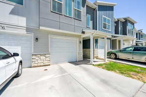 View of side of home with stone siding, driveway, and an attached garage