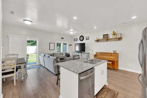 Kitchen featuring stainless steel appliances, light wood-style flooring, white cabinetry, an island with sink, and recessed lighting