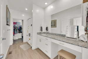 Bathroom with wood finished floors, vanity, and recessed lighting