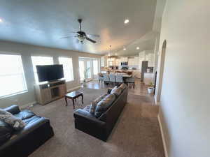 Living area featuring ceiling fan, arched walkways, carpet floors, recessed lighting, and vaulted ceiling