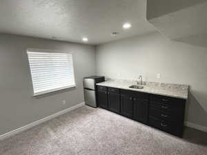 Basement Bar area with freestanding refrigerator, a textured ceiling, light carpet, and recessed lighting
