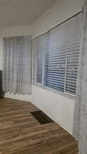Empty room featuring crown molding, wood finished floors, an ornate ceiling, and healthy amount of natural light