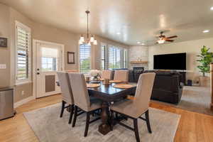 Dining room featuring healthy amount of natural light, light wood finished floors, a fireplace, recessed lighting, and a ceiling fan