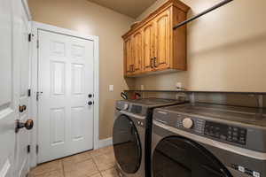 Laundry area featuring cabinet space, washer and dryer, and light tile patterned flooring