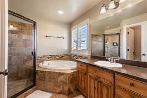 Full bathroom featuring a garden tub, a shower stall, vanity, and tile patterned flooring