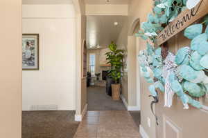 Entrance foyer featuring light colored carpet, light tile patterned flooring, arched walkways, and a fireplace