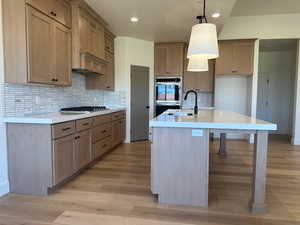 Kitchen featuring recessed lighting, marble backsplash, light wood-style flooring, stainless steel double oven, full walk in pantry, and light quartz countertops