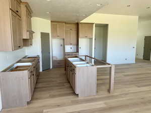 Kitchen with a center island with sink, light wood-style flooring, recessed lighting, and a textured ceiling