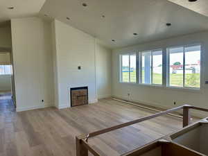Unfurnished living room featuring lofted ceiling, a fireplace, light wood-style floors, and a textured ceiling