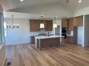 Kitchen with vaulted ceiling, decorative marble backsplash, light quartz countertops, recessed lighting, and decorative light fixtures