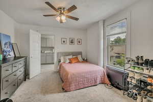 Bedroom with light colored carpet, ensuite bathroom, and a ceiling fan