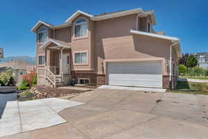 View of front of house with brick siding, driveway, and stucco siding
