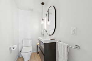 Half bath with vanity and wood finished floors