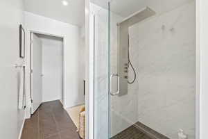 Full bathroom featuring a marble finish shower and tile patterned flooring
