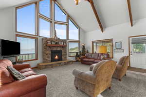 Carpeted living room with high vaulted ceiling, a fireplace, and beamed ceiling