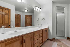 Full bathroom featuring double vanity and a stall shower