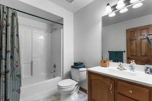 Full bath with shower / bath combo with shower curtain, vanity, and tile patterned flooring