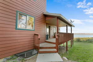 Deck with a water view and a lawn
