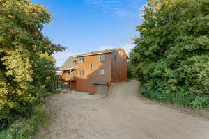 Rear view of property with driveway, a garage, and a wooden deck