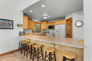 Kitchen featuring white appliances, a peninsula, light countertops, and recessed lighting