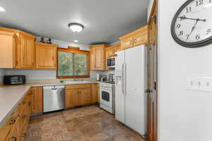 Kitchen with stainless steel appliances, light countertops, dark stone finish floors, and recessed lighting