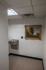 Hall featuring a paneled ceiling and carpet flooring