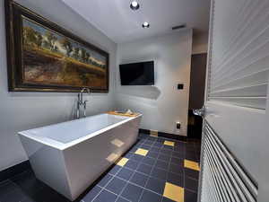 Bathroom with a freestanding bath, tile patterned floors, and recessed lighting