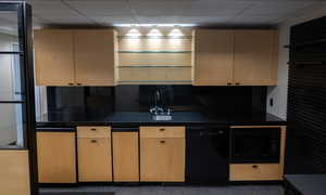 Kitchen with black appliances, a drop ceiling, dark countertops, and light brown cabinets