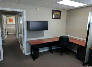 Carpeted office space featuring a paneled ceiling and baseboards