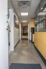 Hall with finished concrete flooring and a paneled ceiling