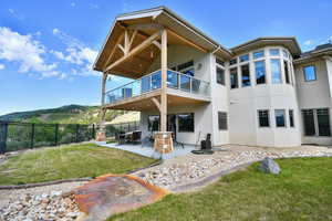 Back of house with a balcony, stucco siding, a patio, and a mountain view