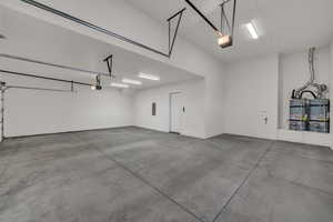 Garage featuring water heater, a garage door opener, and electric panel