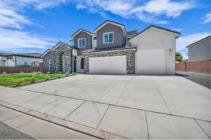 View of front of home featuring board and batten siding, stone siding, driveway, and a garage