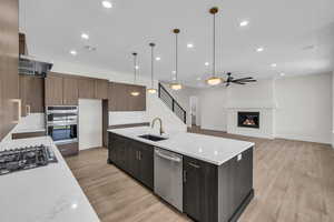 Kitchen featuring stainless steel appliances, light wood-style flooring, a glass covered fireplace, recessed lighting, and ceiling fan