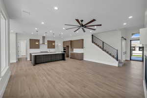 Unfurnished living room with light wood finished floors, recessed lighting, a ceiling fan, and stairs