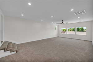 Carpeted spare room featuring recessed lighting, ceiling fan, and stairs