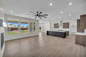 Unfurnished living room featuring recessed lighting, light wood-type flooring, ceiling fan, and a glass covered fireplace