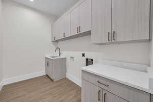Laundry room with electric dryer hookup, washer hookup, light wood-style floors, and cabinet space