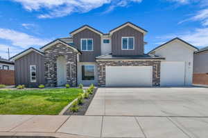 View of front of property featuring board and batten siding, stone siding, driveway, and a front lawn