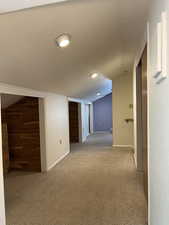 Corridor featuring carpet flooring, vaulted ceiling, and cedar lined storage areas