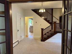 Dining Room  with baseboard heating, carpet flooring, ornamental molding, stairway, and a chandelier