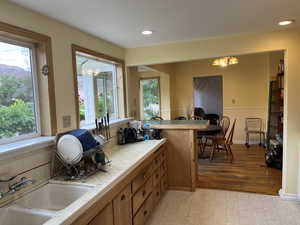 Kitchen featuring tile counters, a chandelier, brown cabinetry, recessed lighting, and decorative backsplash