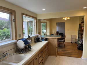 Kitchen featuring tile countertops, healthy amount of natural light, recessed lighting, brown cabinets, and a chandelier