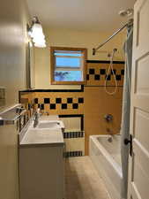 Bathroom featuring radiator, tile walls, vanity, shower / tub combo, and tile patterned floors