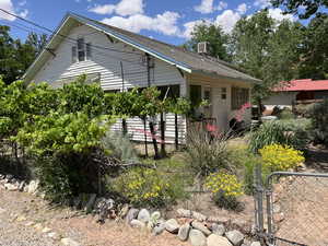 Back of property featuring a gate, central AC unit, and roof with shinglesSE corner of house from sidewalk