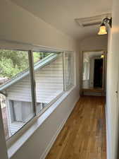 Hall with vaulted ceiling and hardwood / wood-style floors