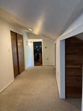 Hall featuring lofted ceiling and carpet floors