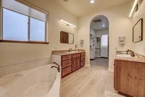 Full bath featuring wood finished floors, two vanities, plenty of natural light, and recessed lighting