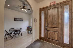 Foyer with arched walkways, ceiling fan, light wood-style floors, and recessed lighting